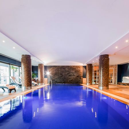 Amora Hotel Jamison Сідней Екстер'єр фото The photo shows an indoor swimming pool. The water is a striking blue color, and the surrounding area has modern decor. There are stone columns supporting the ceiling, and the lighting is bright and inviting. To one side, there are several lounge cha