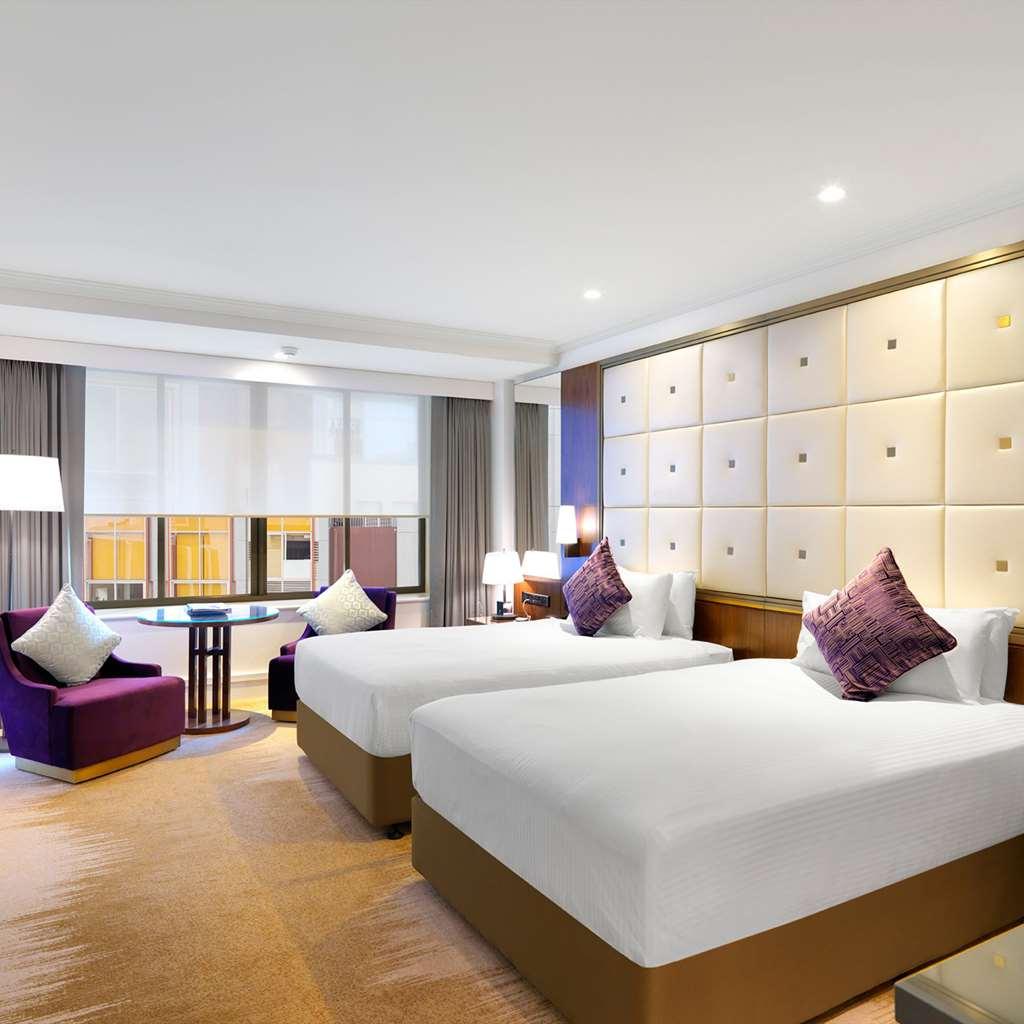 Amora Hotel Jamison Сідней Номер фото The photo depicts a modern hotel room featuring two beds with white linens. The beds are positioned against a wall that has a stylish design with light-colored panels. There are two decorative pillows on each bed. To the side, there is a purple accen